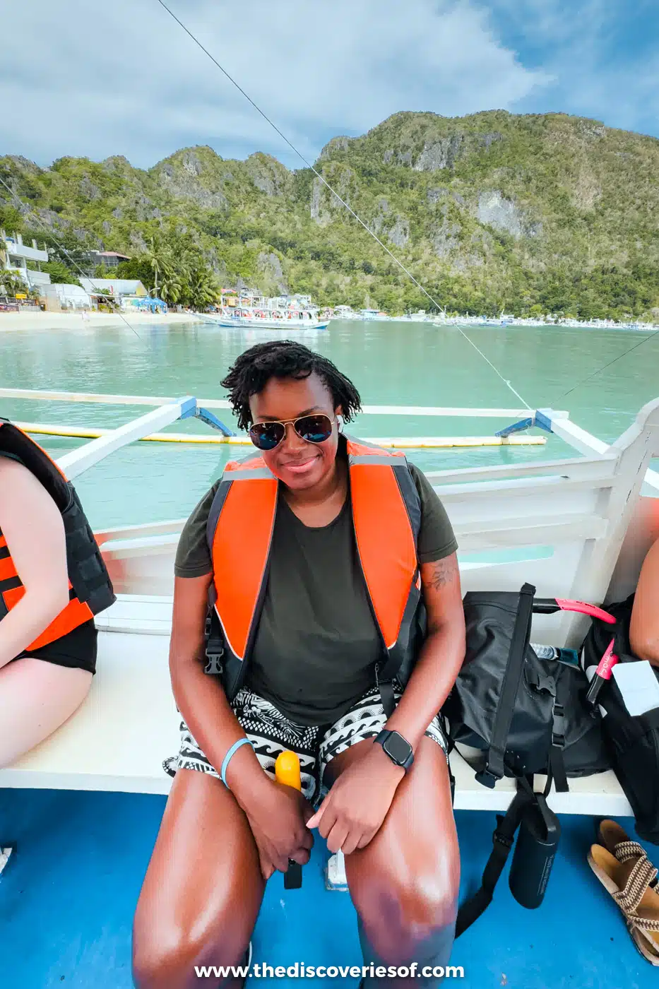 Julianna in an orange life jacket and sunglasses sitting on an island-hopping boat off El Nido town