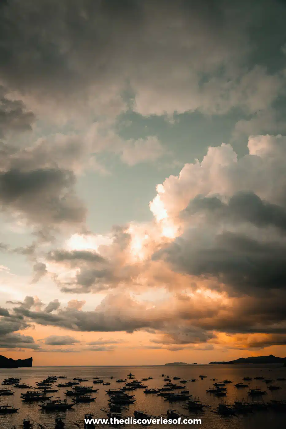 Orange sunset sky and clouds over bangka boats moored in the bay off El Nido town