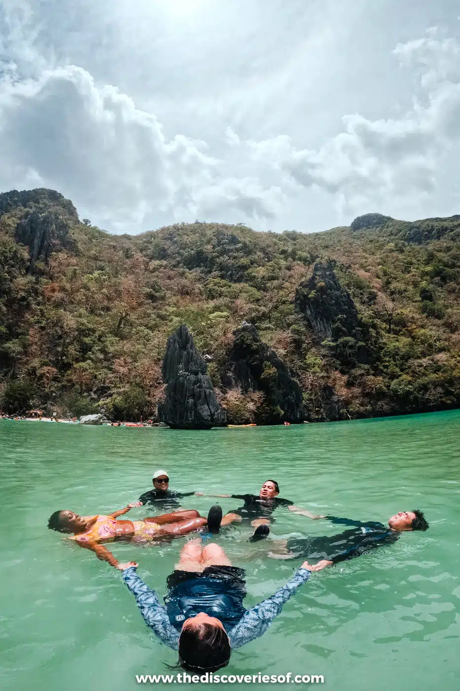 Island hoppers floating on their backs in a star shape in the green water of Cadlao Lagoon, El Nido