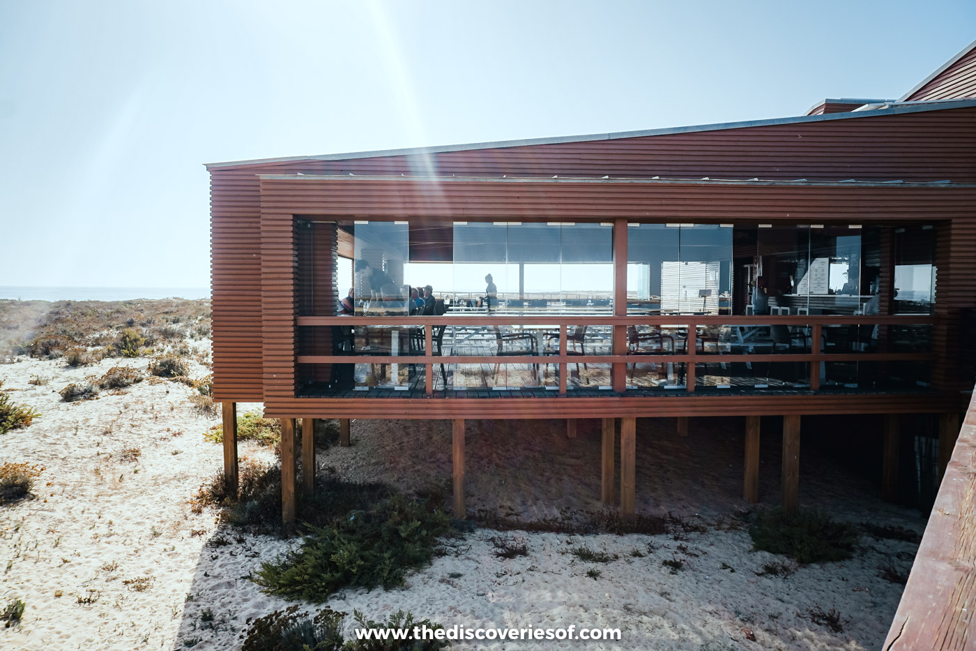 The glass-fronted wooden dining room of Estaminé raised on stilts above the sand and scrub of Ilha Deserta