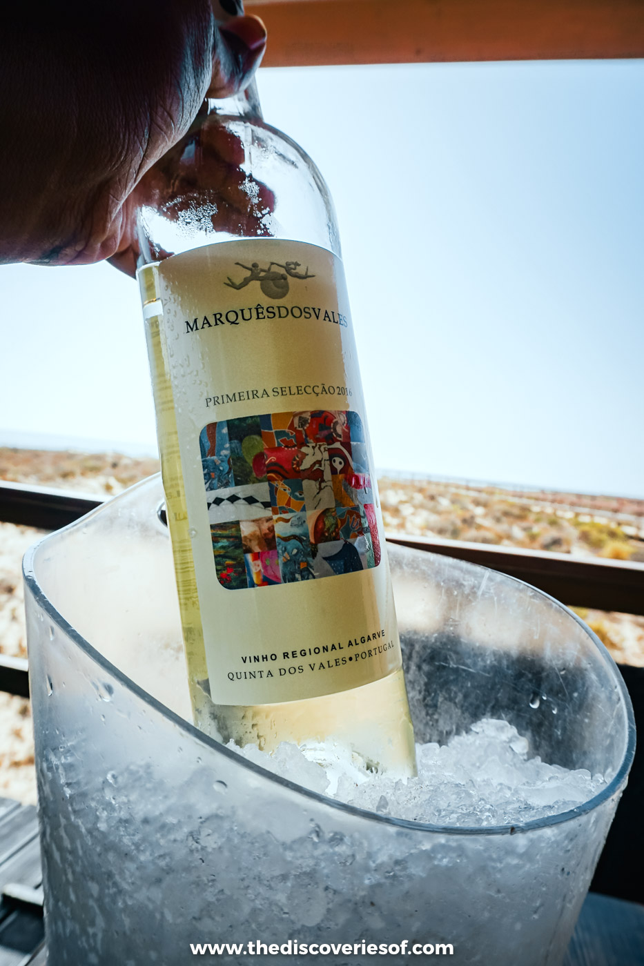 A bottle of Marquês dos Vales Algarve white wine being lowered into an ice bucket on the terrace at Estaminé