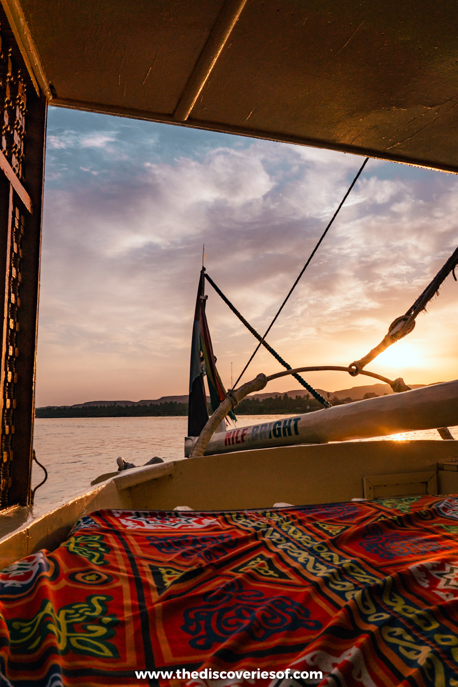 Sun rising over the Nile seen from the deck of a felucca with its rigging and patterned cushions, Egypt