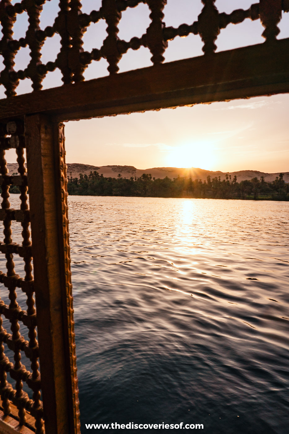 The low sun shining over the Nile, framed by the carved wooden lattice of a felucca canopy