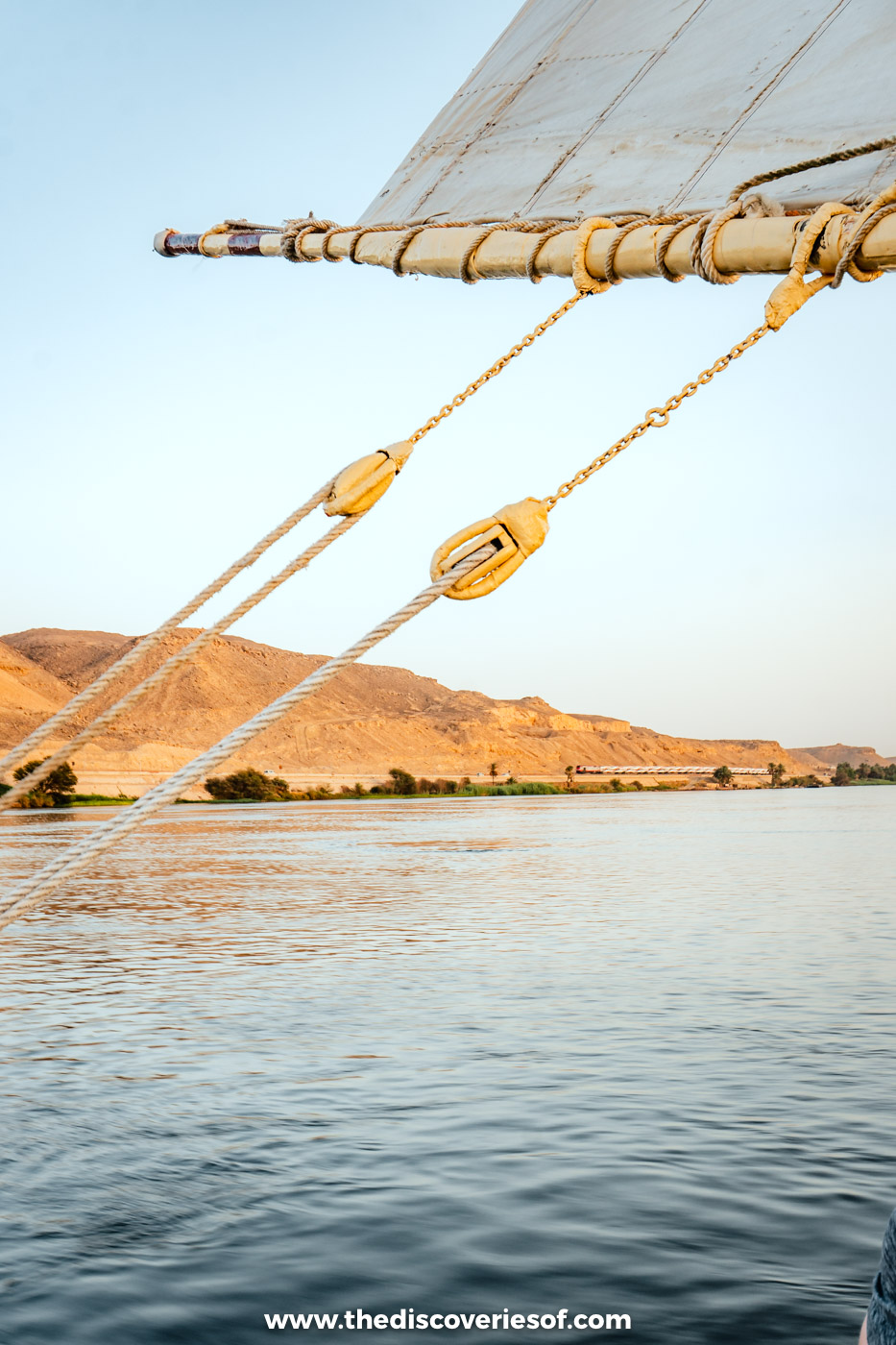 The rigging of a felucca sailing on the Nile between Aswan and Luxor, with desert hills on the bank