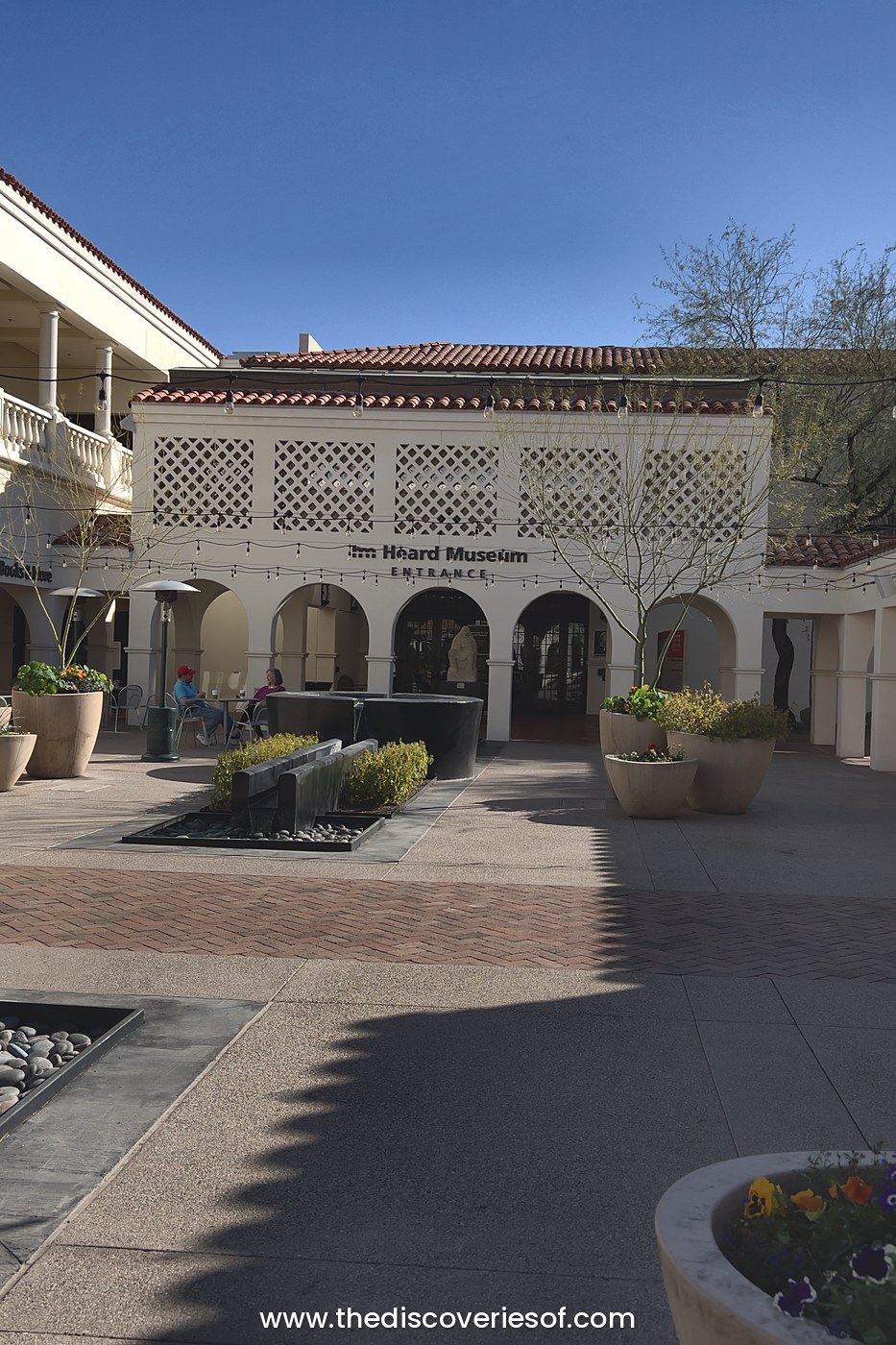 Courtyard with a fountain, planters and arched entrance at the Heard Museum in Phoenix under a blue sky