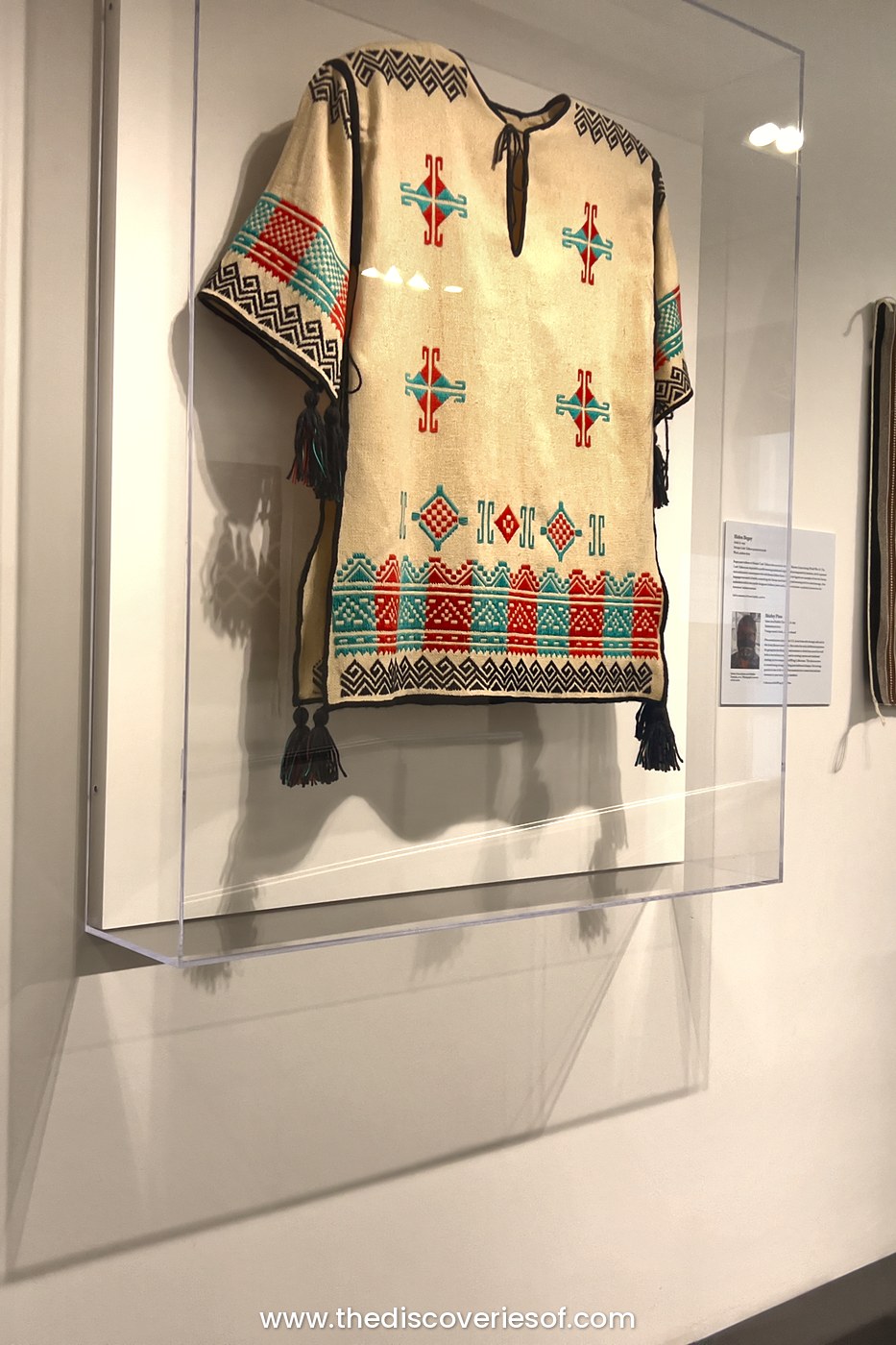 Woven shirt with red and turquoise geometric patterns in a glass case at the Heard Museum, Phoenix