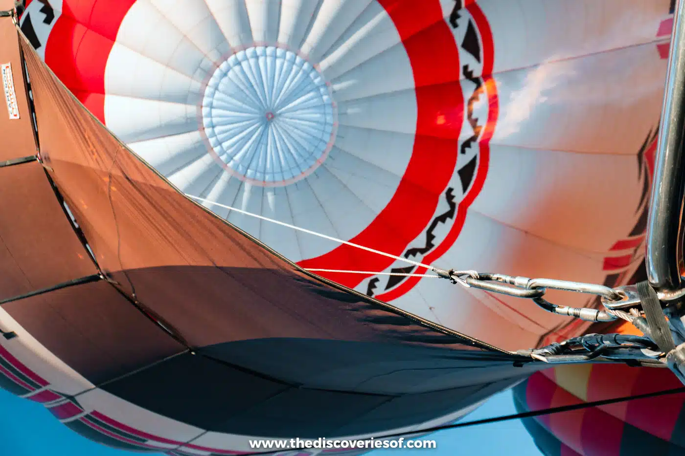 Looking up into a red and white hot air balloon envelope from the basket during a flight over Albuquerque