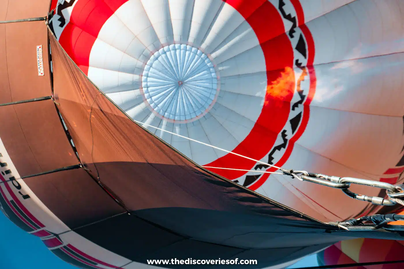 Looking up into a red, white and black hot air balloon as the burner fills it before take-off in Albuquerque