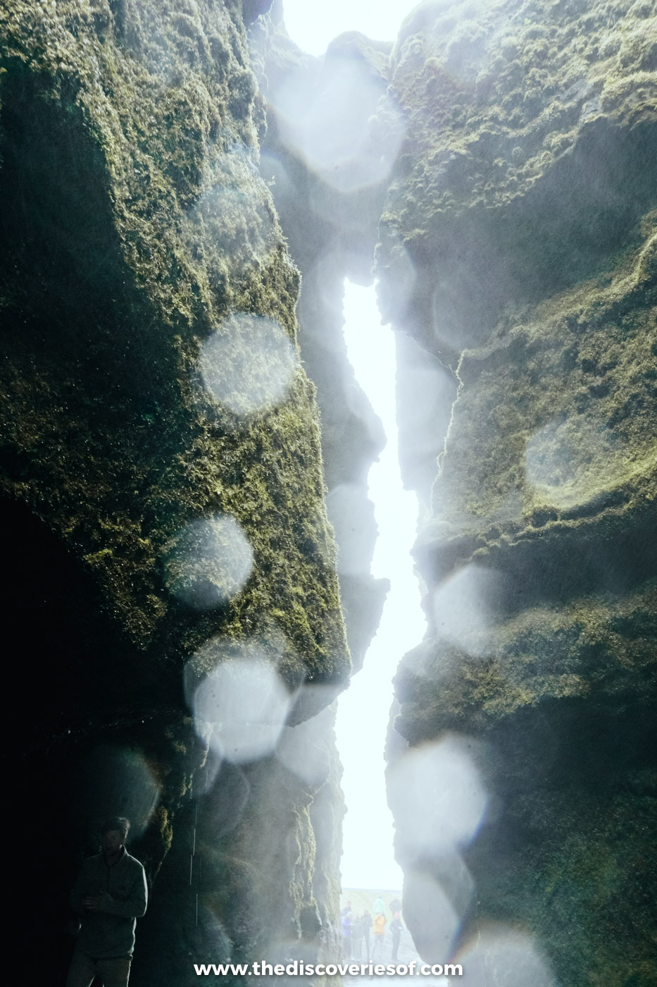 Spray droplets covering the camera lens inside the narrow mossy slot leading into Gljúfrabúi waterfall