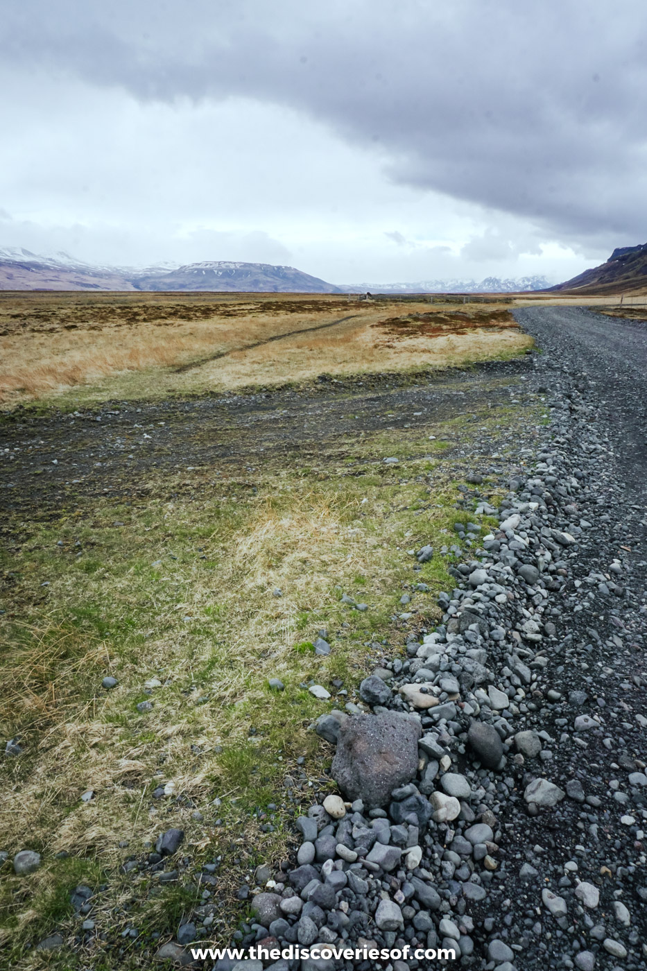 Gravel track and stony verge crossing open moorland towards distant hills on a super jeep day near Þórsmörk