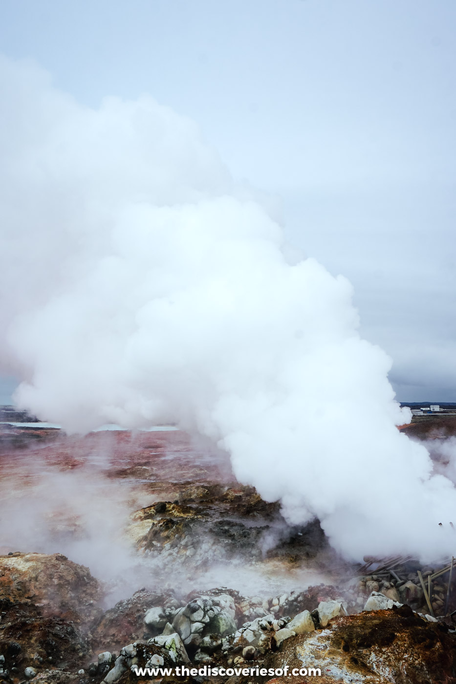 White steam billowing from a geothermal vent and mud pool in a steaming geothermal field in Iceland