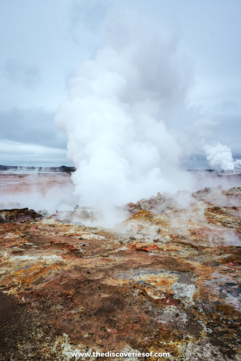 Clouds of white steam billowing from a geothermal vent across red-brown ground at Gunnuhver on the Reykjanes peninsula