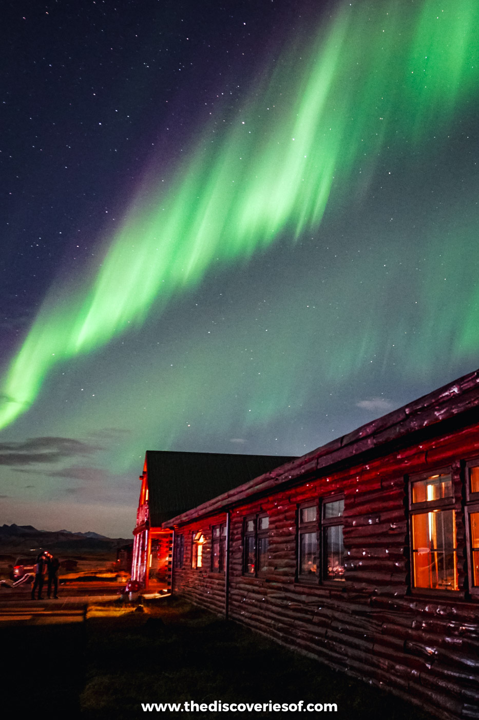 Green Northern Lights rising above the log wing of Hotel Rangá near Hella on a clear September night