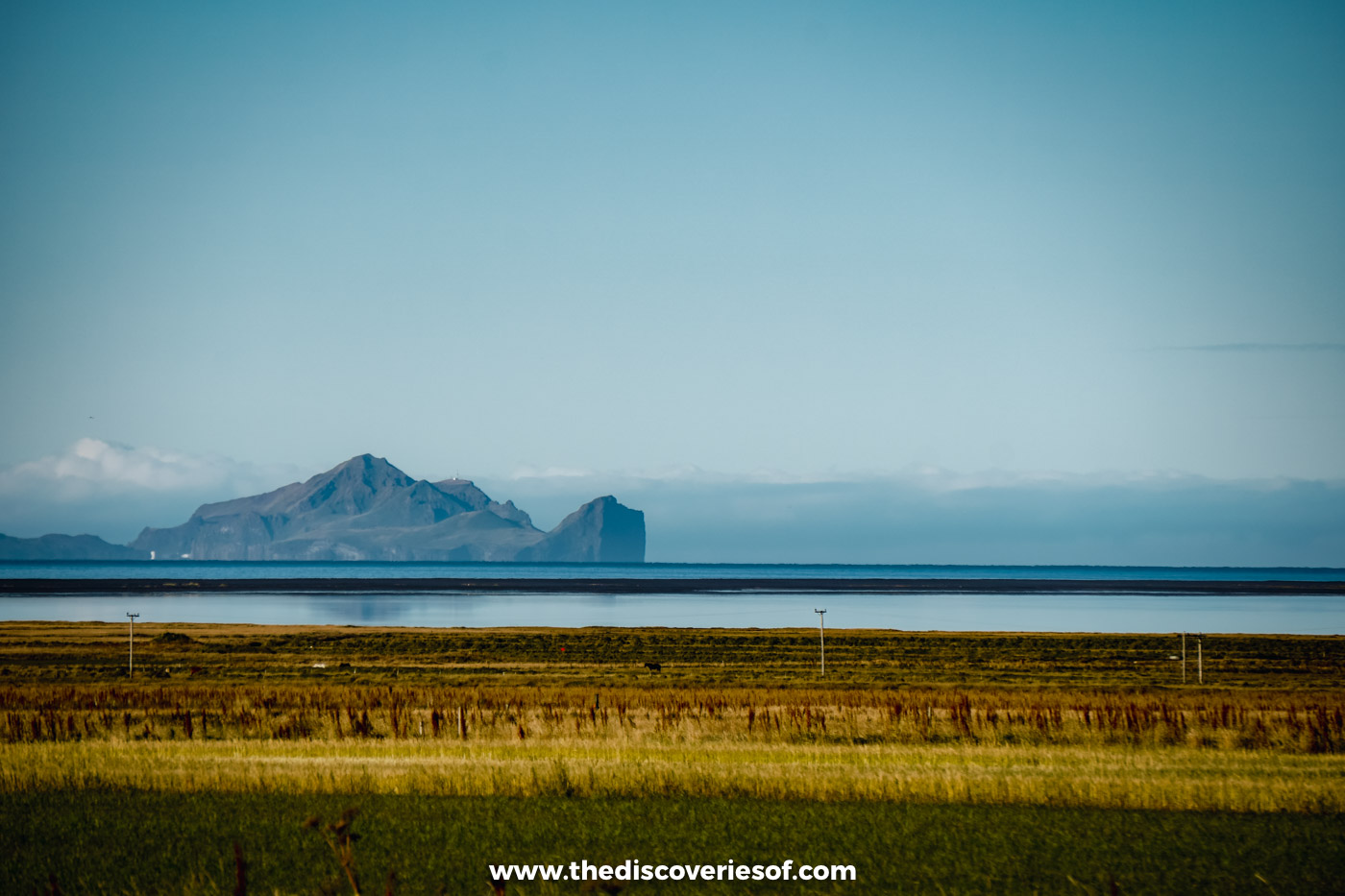 The Westman Islands rising beyond green fields on the south coast of Iceland in September