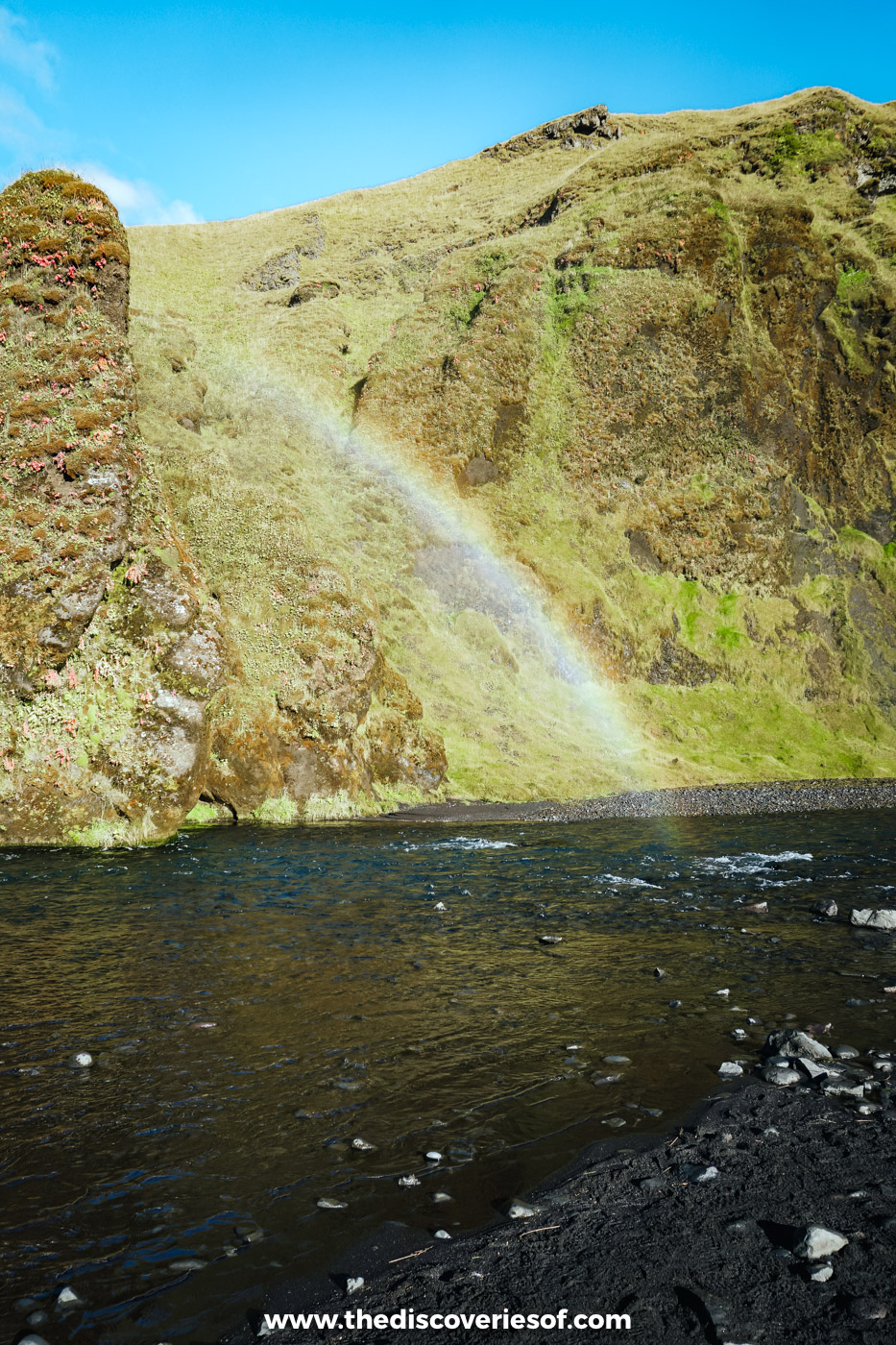 A rainbow in the spray over the shingle and river below Skógafoss on a sunny September day