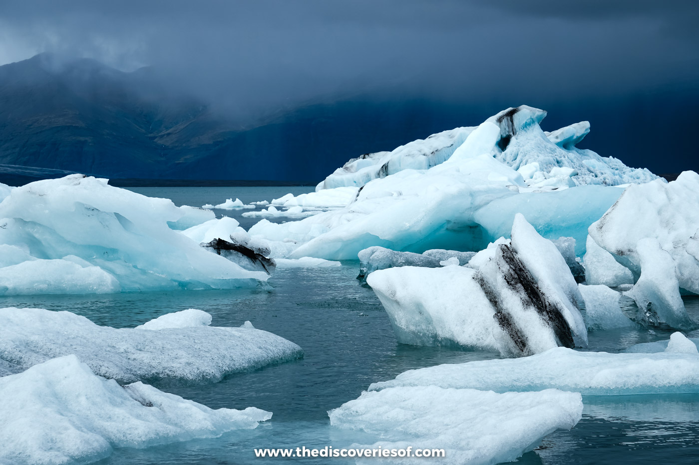 Icebergs striped with black bands of volcanic ash floating on Jökulsárlón glacier lagoon