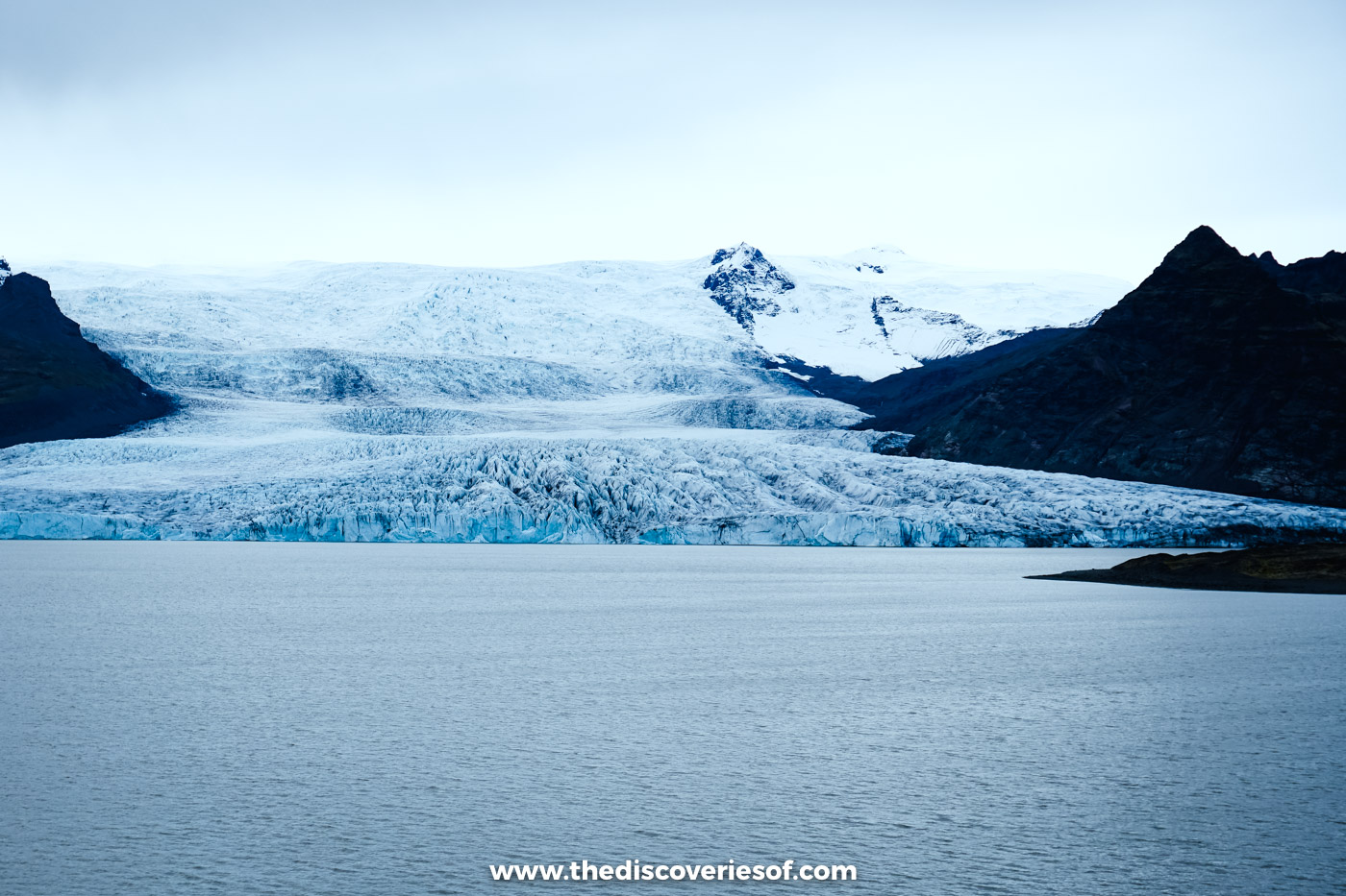 The crevassed tongue of Fjallsjökull glacier meeting the grey water of Fjallsárlón lagoon in South Iceland