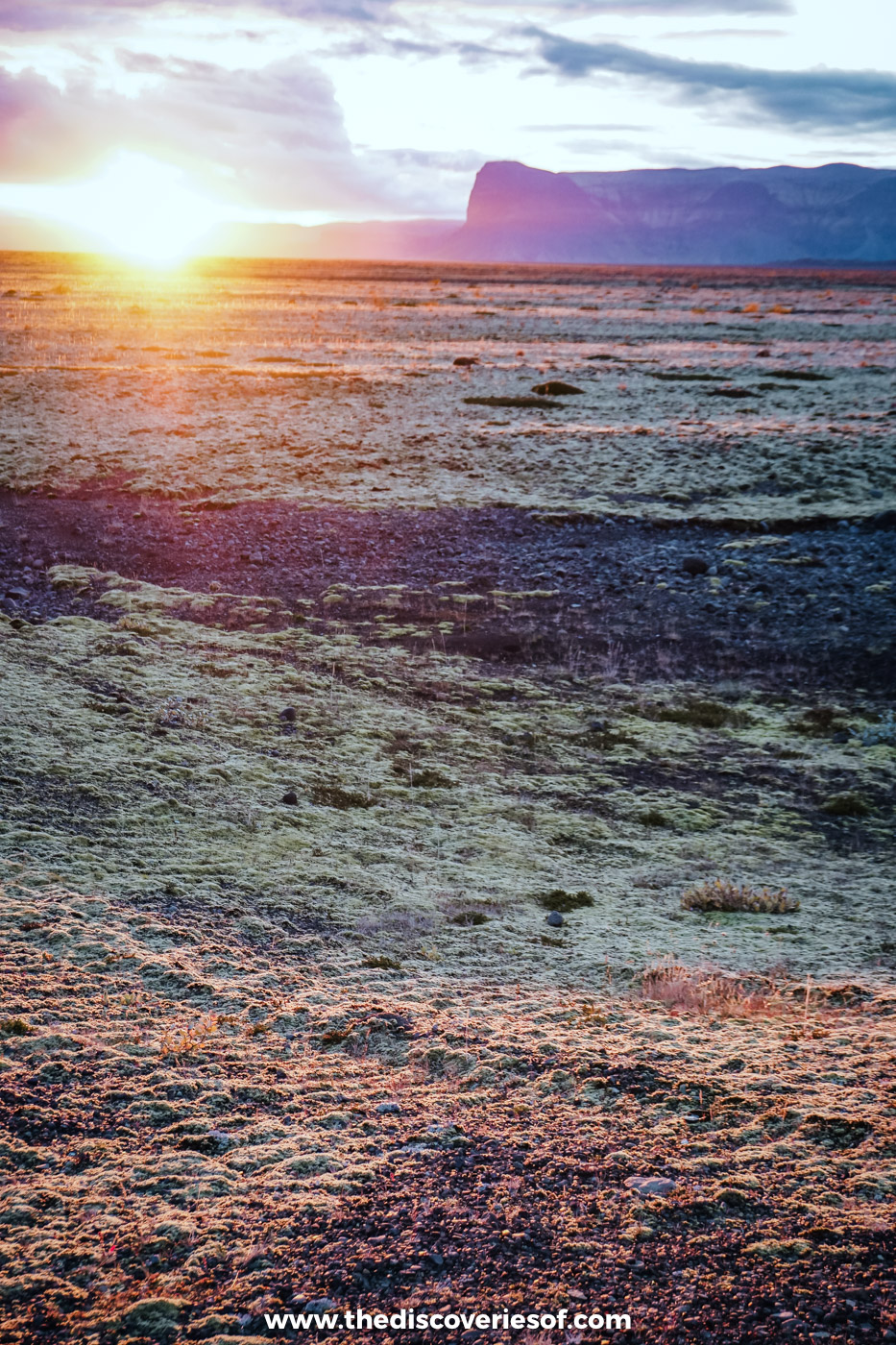 The sun sinking towards flat-topped mountains over russet moss and lava fields beside the Ring Road in south Iceland