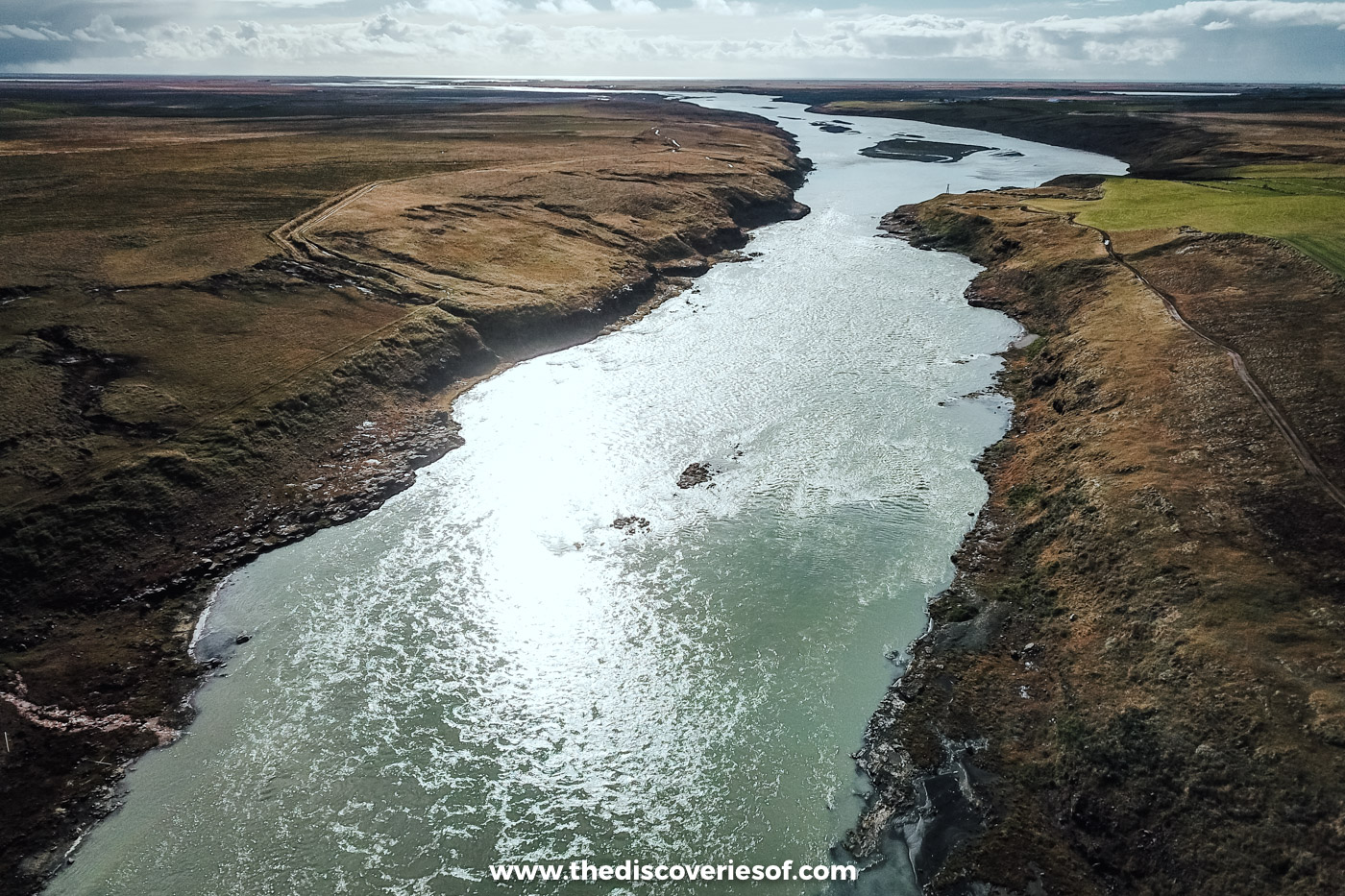 Aerial view of the wide Þjórsá river glinting in the sun between low banks and moorland near Urriðafoss