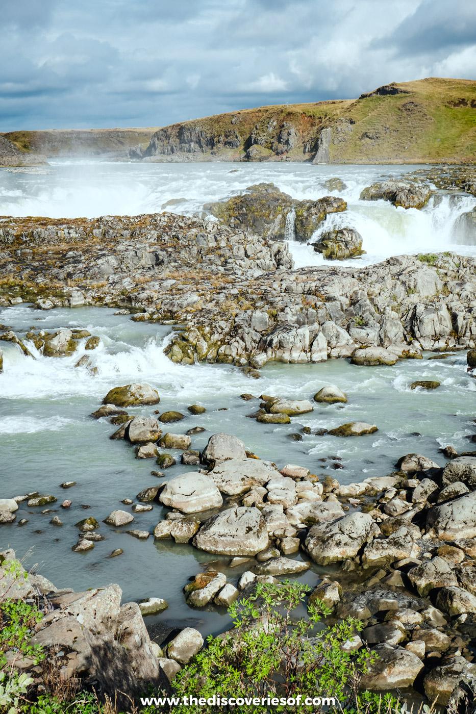 Urriðafoss tumbling over a broad ledge of dark rock on the Þjórsá river, with boulders and rapids in front