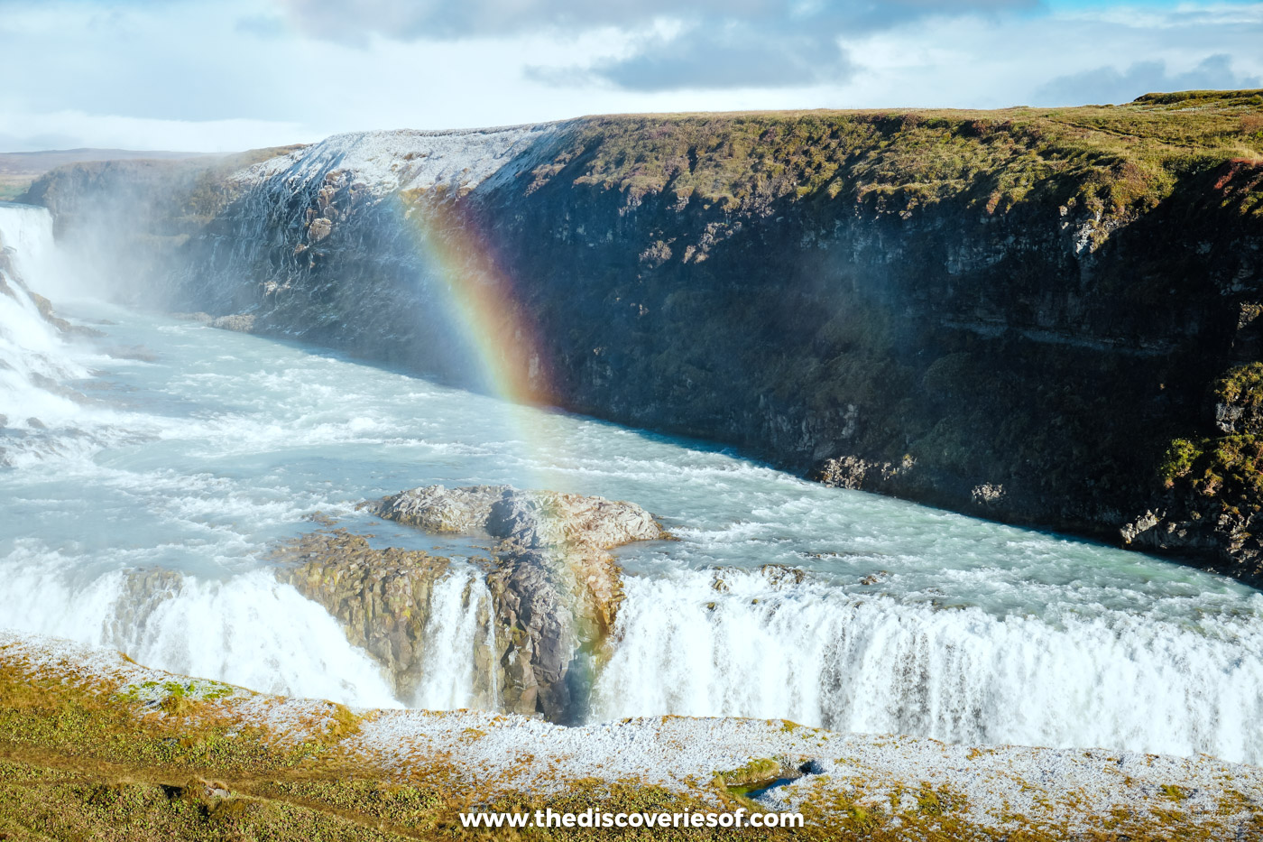 A rainbow arcing through the spray above the tiered falls and canyon of Gullfoss on a bright day