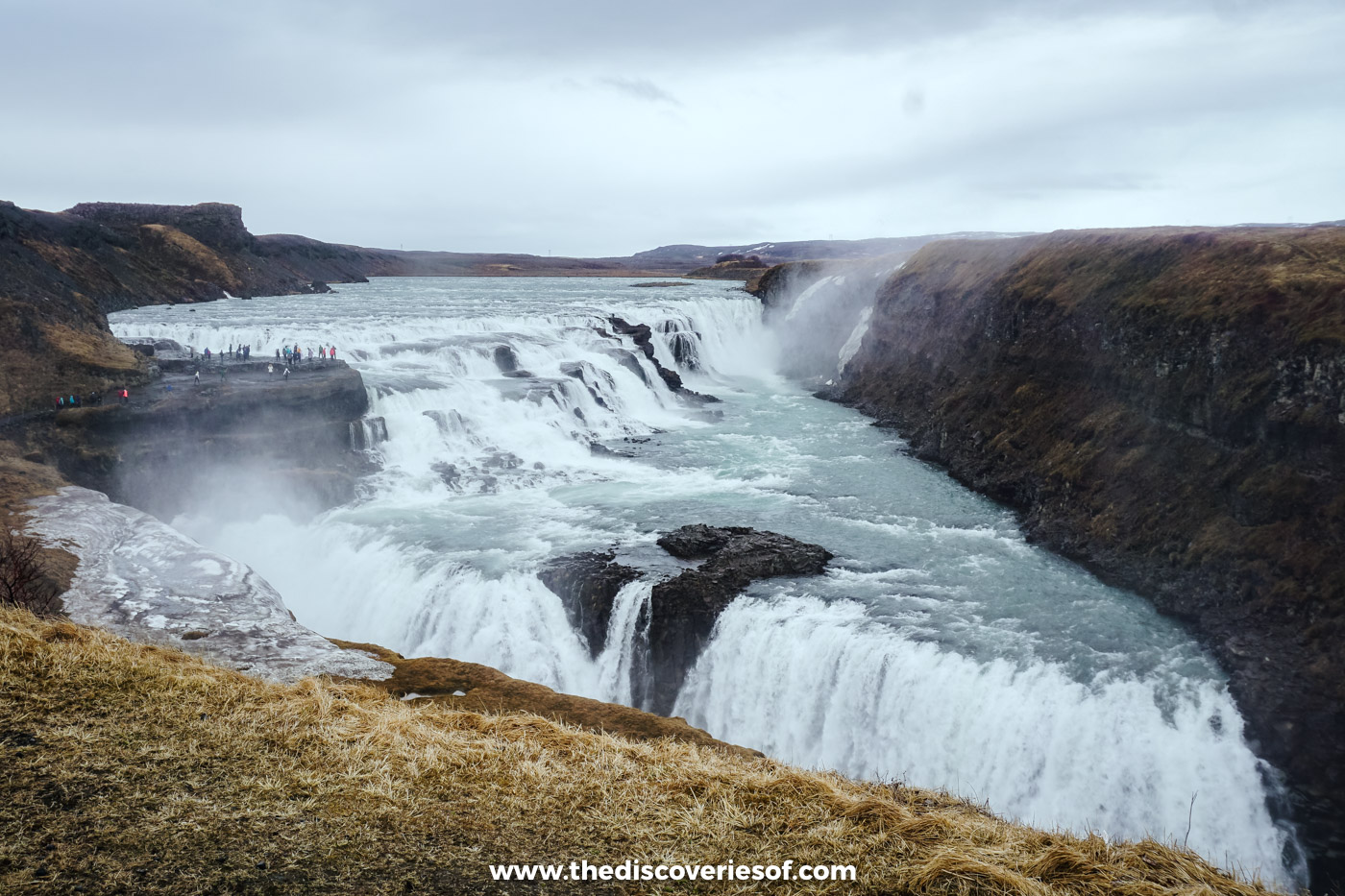 Gullfoss and its canyon under a white sky in early May, with snow still lying on the canyon walls