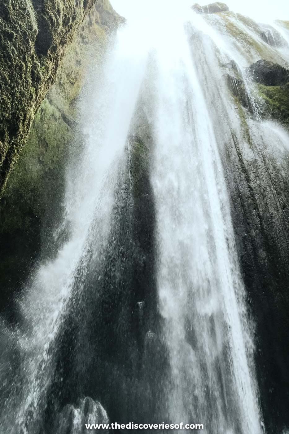 Looking up at Gljúfrabúi waterfall pouring into its narrow mossy chamber near Seljalandsfoss