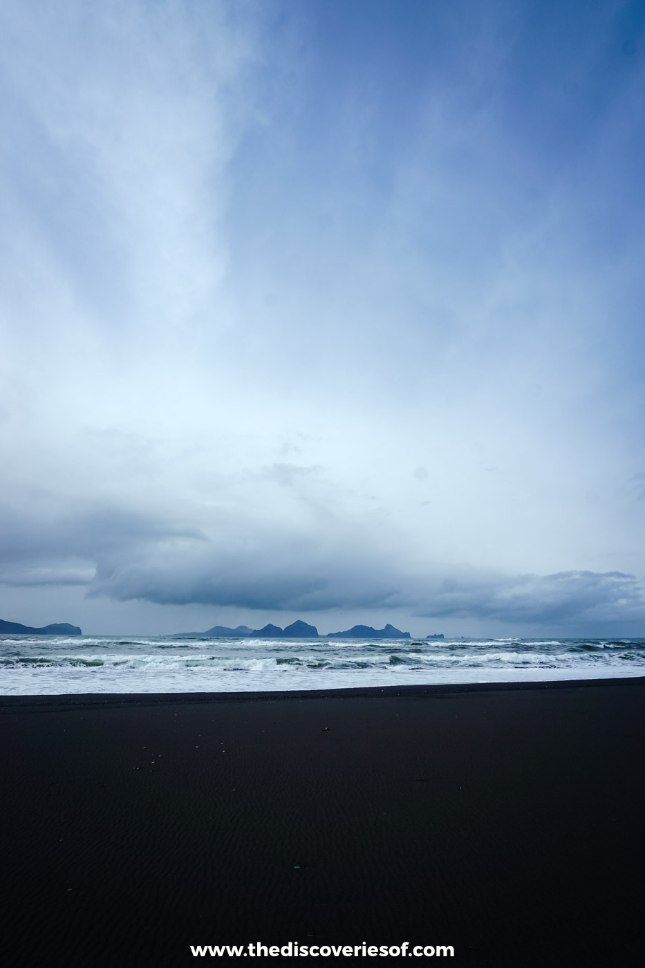Flat black sand and a line of surf with the Westman Islands faint on the horizon at Landeyjafjara