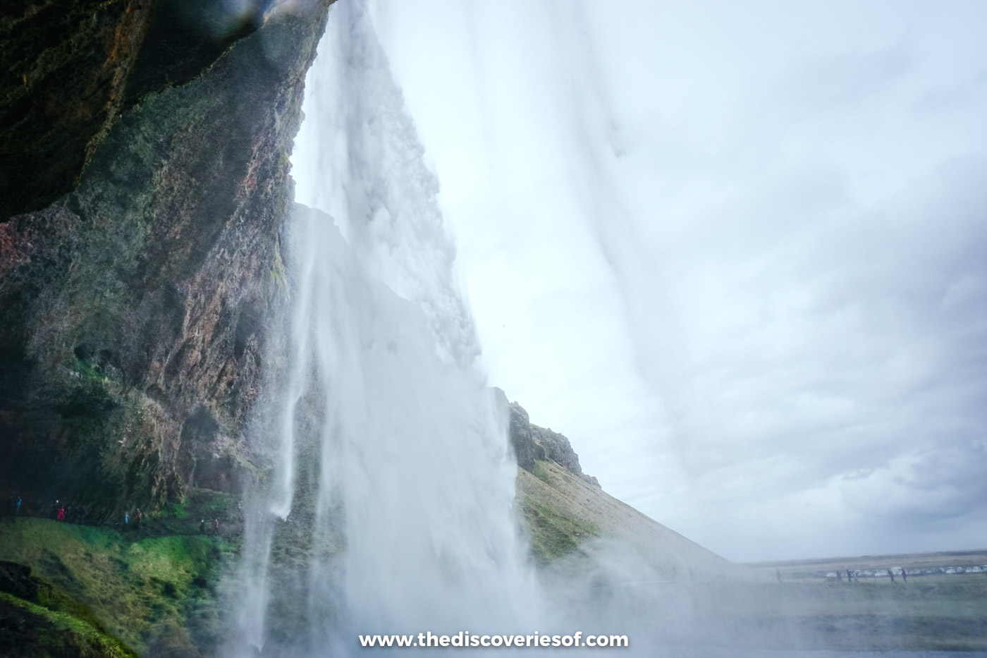 View from the hollow behind Seljalandsfoss, looking out through the falling water to the flat plain beyond