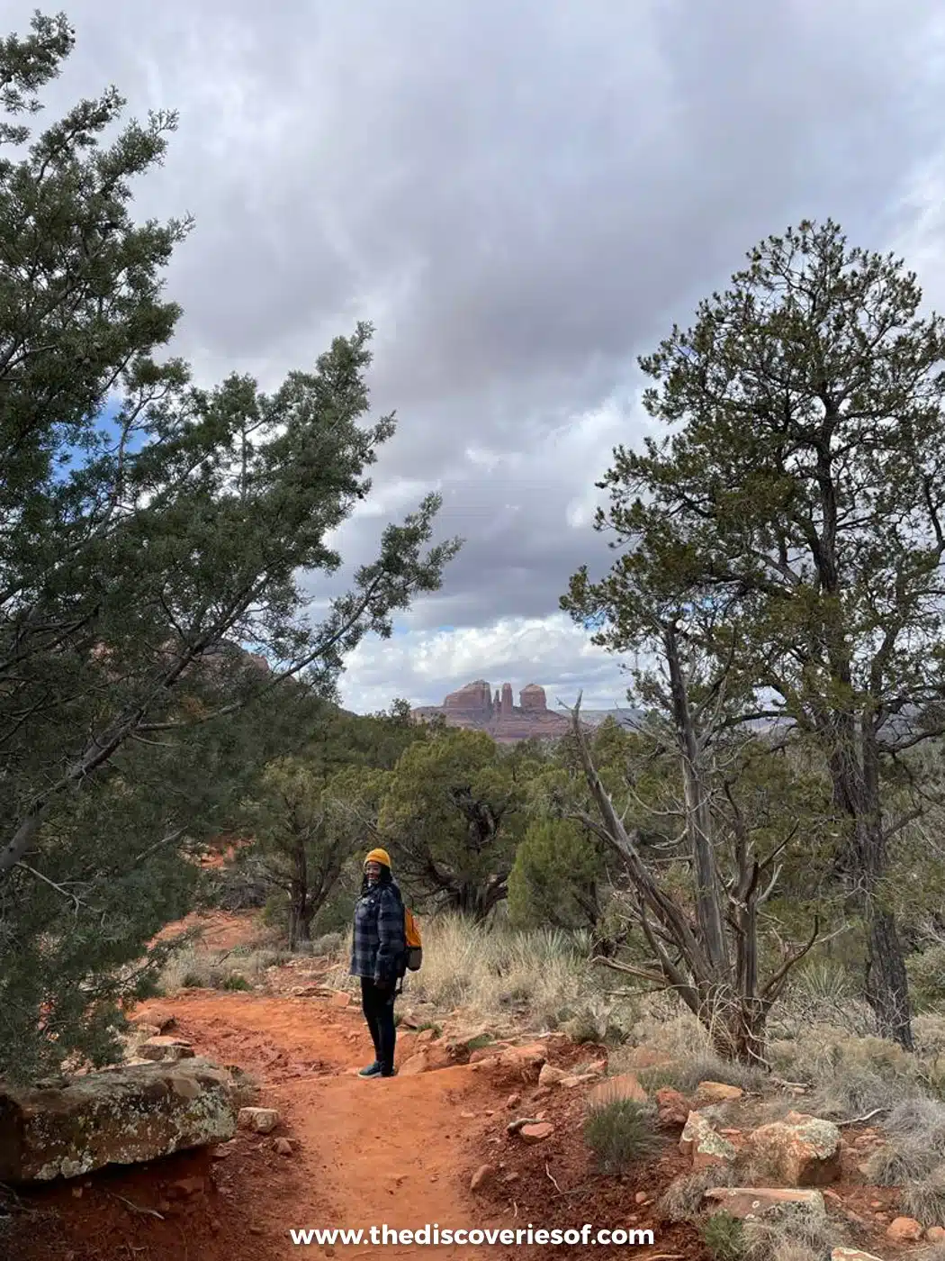 Julianna Barnaby walking a red dirt trail through juniper woodland on the Courthouse Butte Loop, Sedona