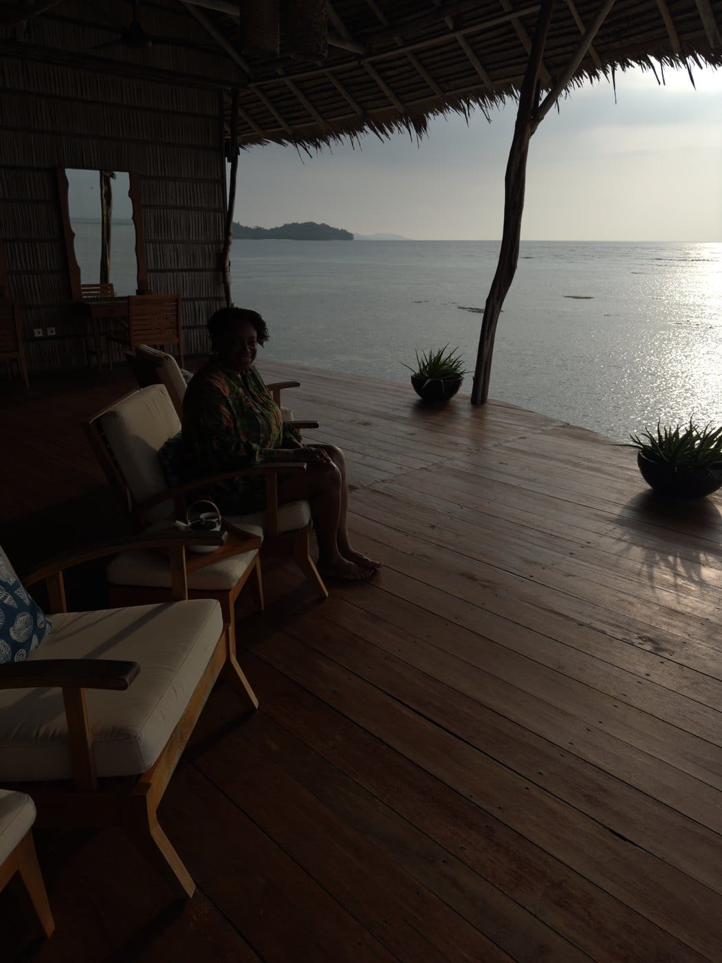 Julianna relaxing in an armchair on the spa deck at Papua Paradise, with a teapot beside her and the calm sea beyond