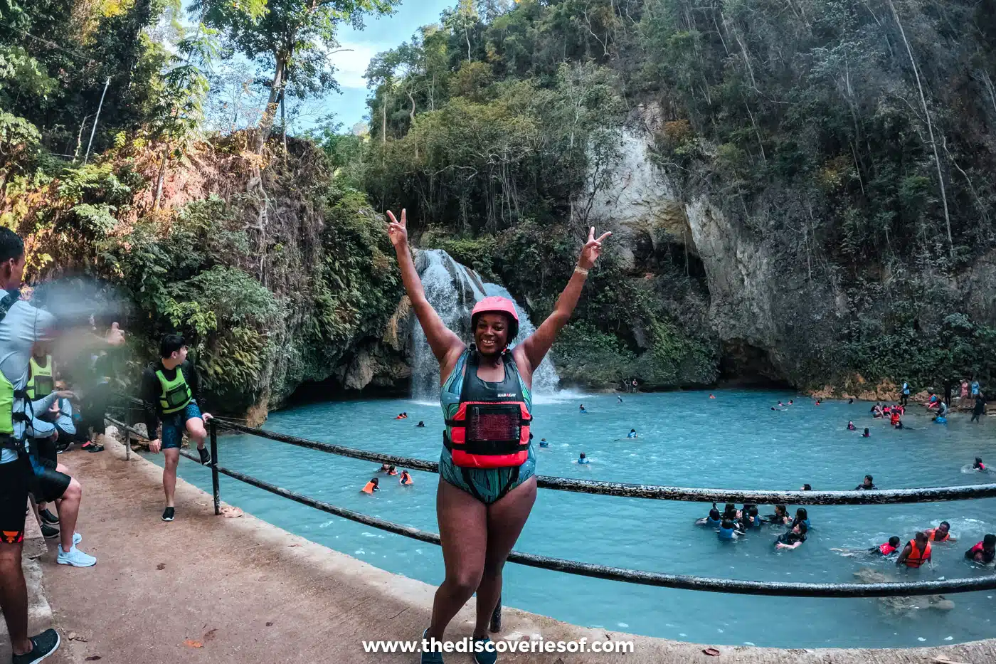Julianna in a helmet and life jacket beside the busy lower pool at Kawasan Falls, Badian, Cebu