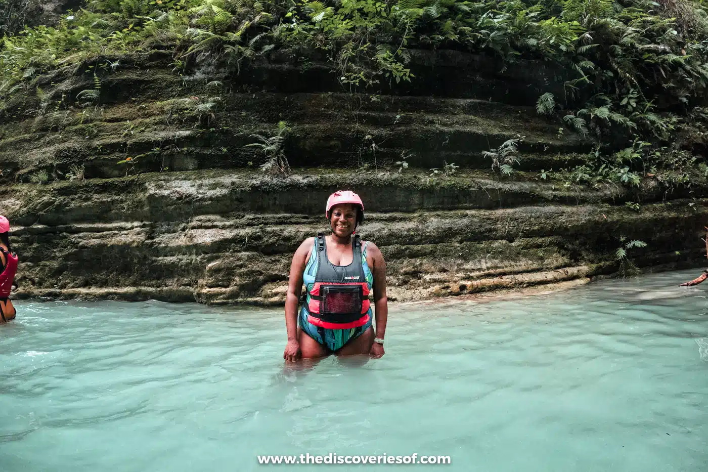 Julianna waist-deep in a turquoise pool below layered rock walls in the canyon near Kawasan Falls, Cebu