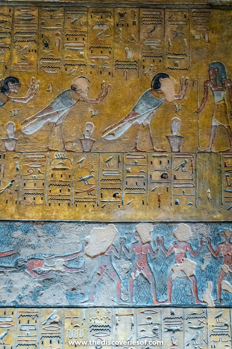 Registers of painted figures and hieroglyphs from the Book of the Earth on a yellow wall in tomb KV14