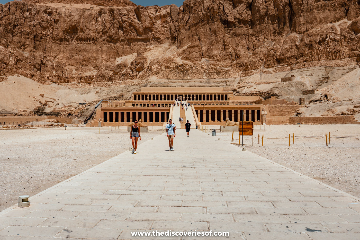Paved approach leading to the three terraces of the Mortuary Temple of Hatshepsut below golden limestone cliffs