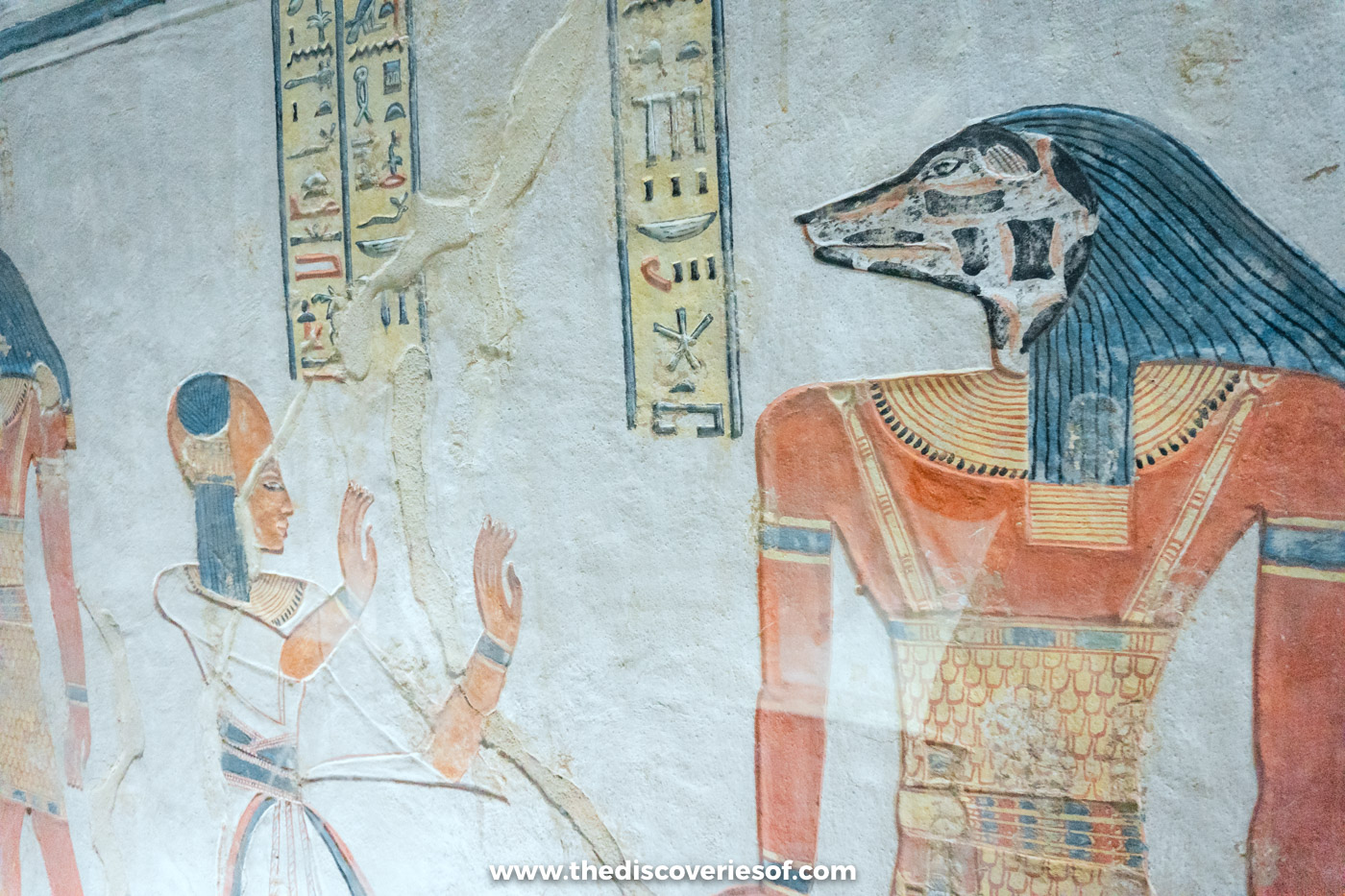 Painted relief of young Prince Khaemwaset with a sidelock before a jackal-headed god in tomb QV44