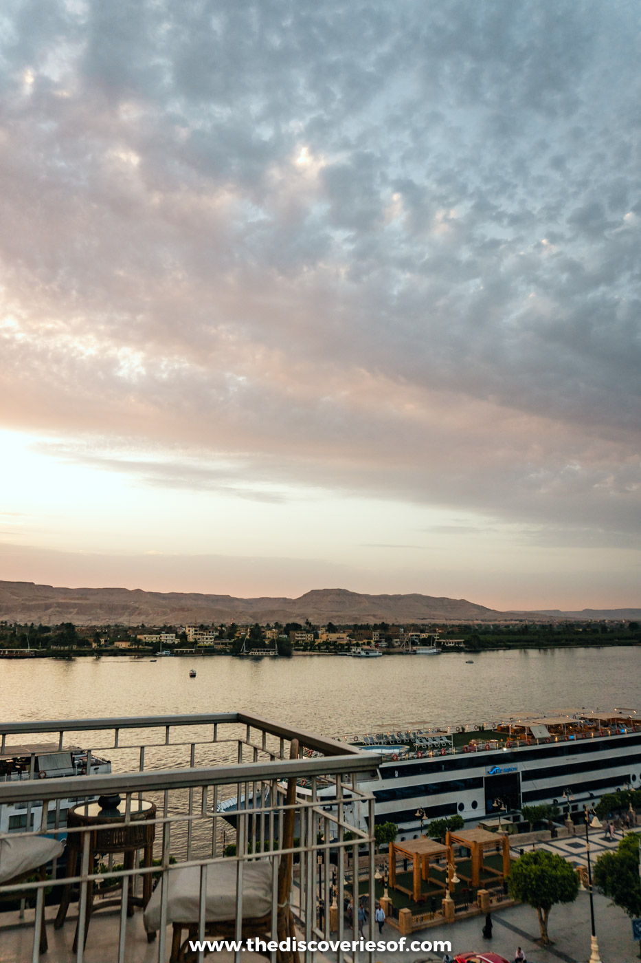 View across the Nile from an East Bank balcony to the West Bank and the Theban hills at dusk, Luxor
