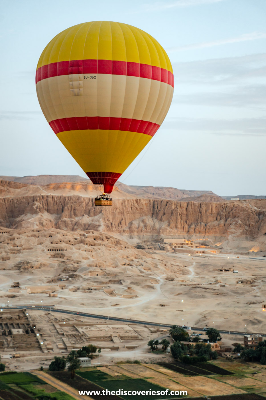 Hot air balloon above the Theban cliffs with the terraced Mortuary Temple of Hatshepsut below, Luxor