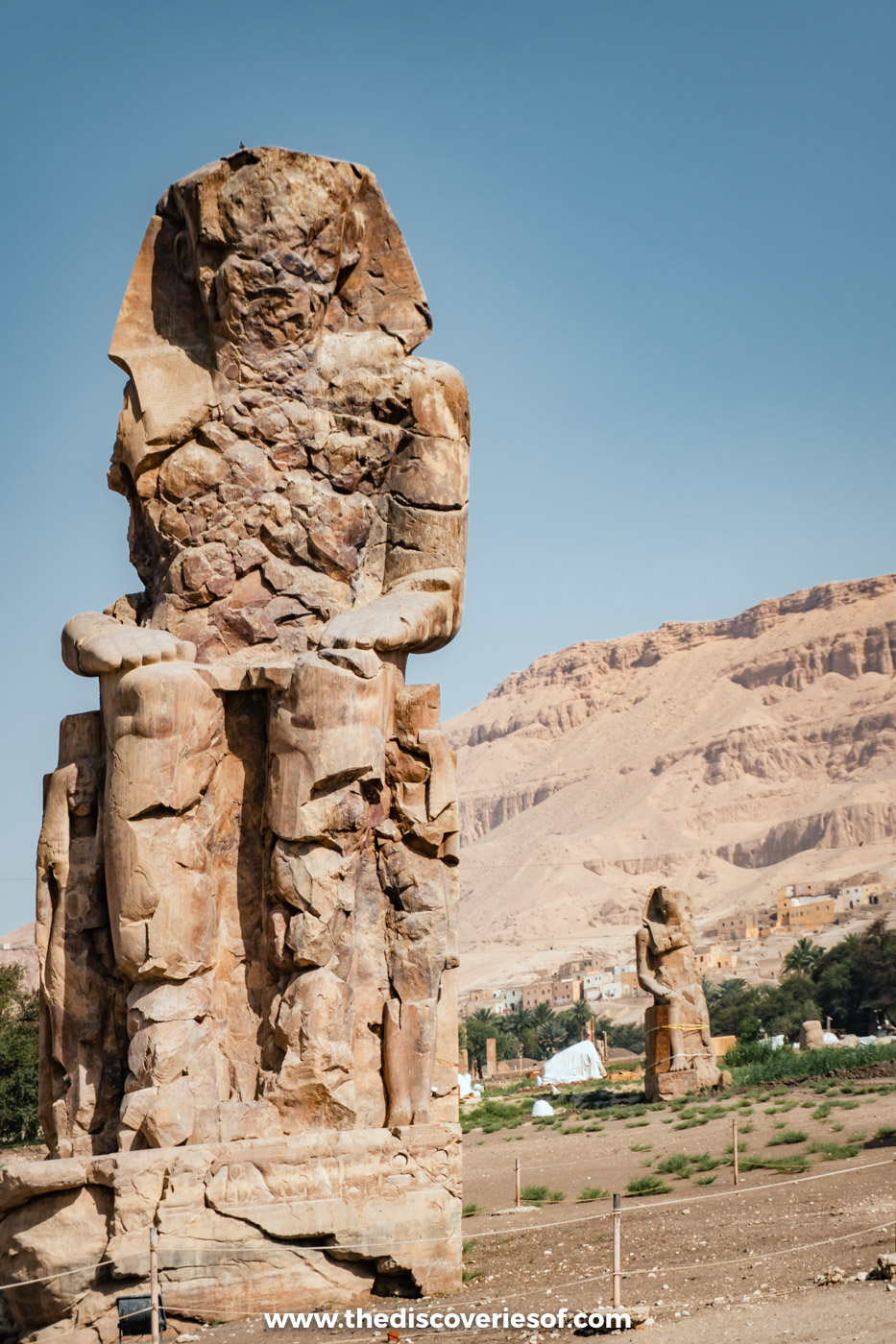 One of the seated Colossi of Memnon, worn by time, against the Theban hills on Luxor's West Bank