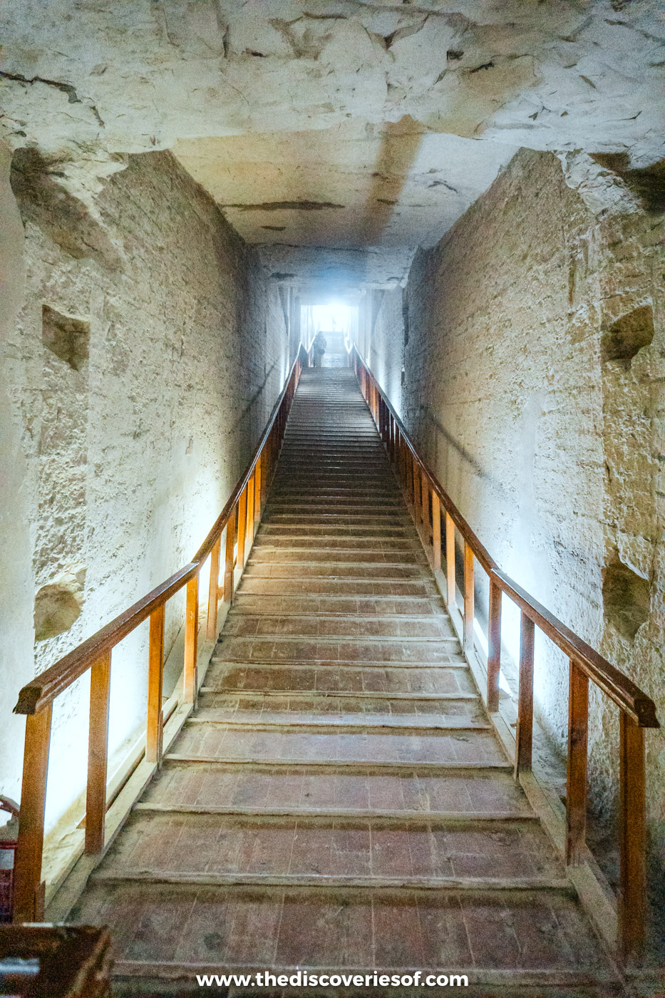 Long wooden stairway with handrails descending through a plain corridor in the tomb of Merenptah, KV8
