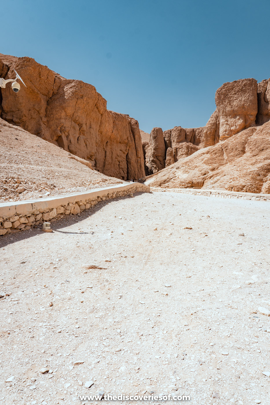Gravel path leading between steep sunlit cliffs into the upper Valley of the Kings, Luxor