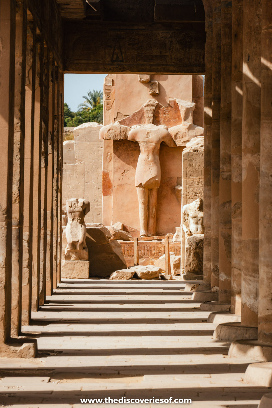 A shaded colonnade with steps leading to a standing statue of the pharaoh at Karnak Temple in Luxor