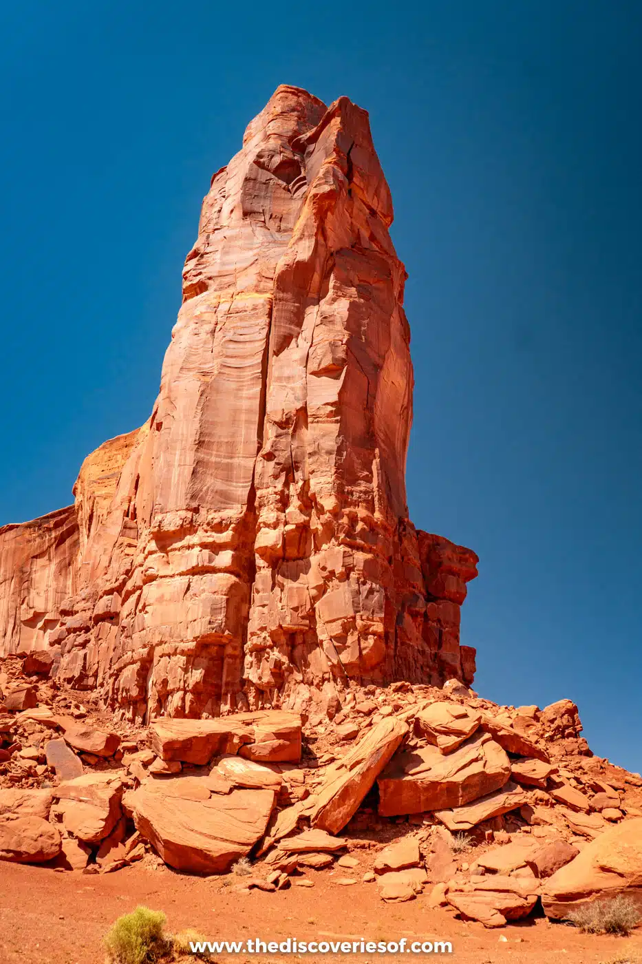 Tall red sandstone tower above a rocky slope near the Elephant Butte stop in Monument Valley
