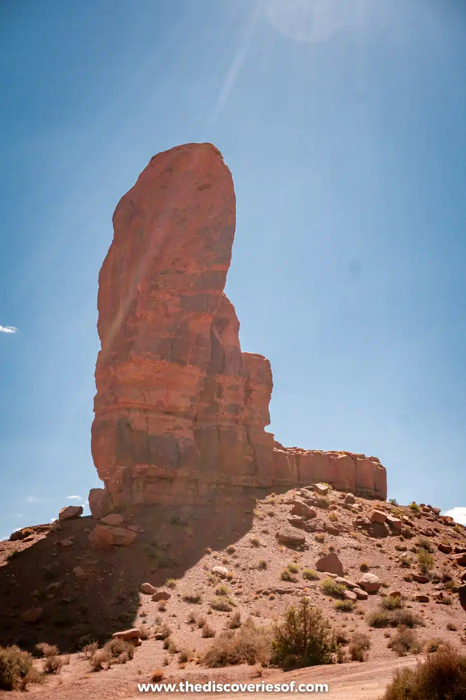 The Thumb, a rounded sandstone pinnacle against a bright sky in Monument Valley