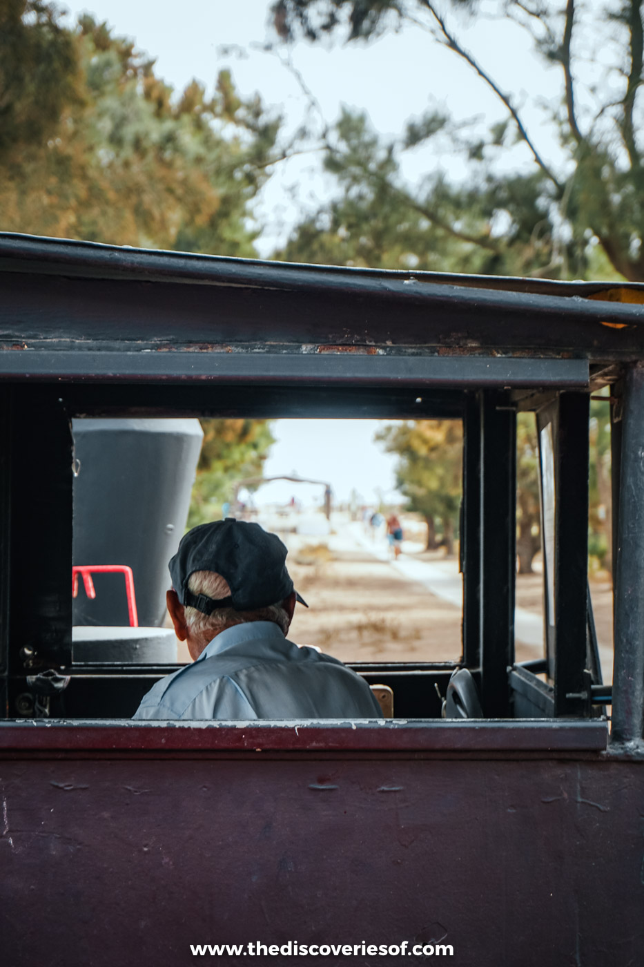 View through an open carriage of the Praia do Barril train to the driver in a cap at the front