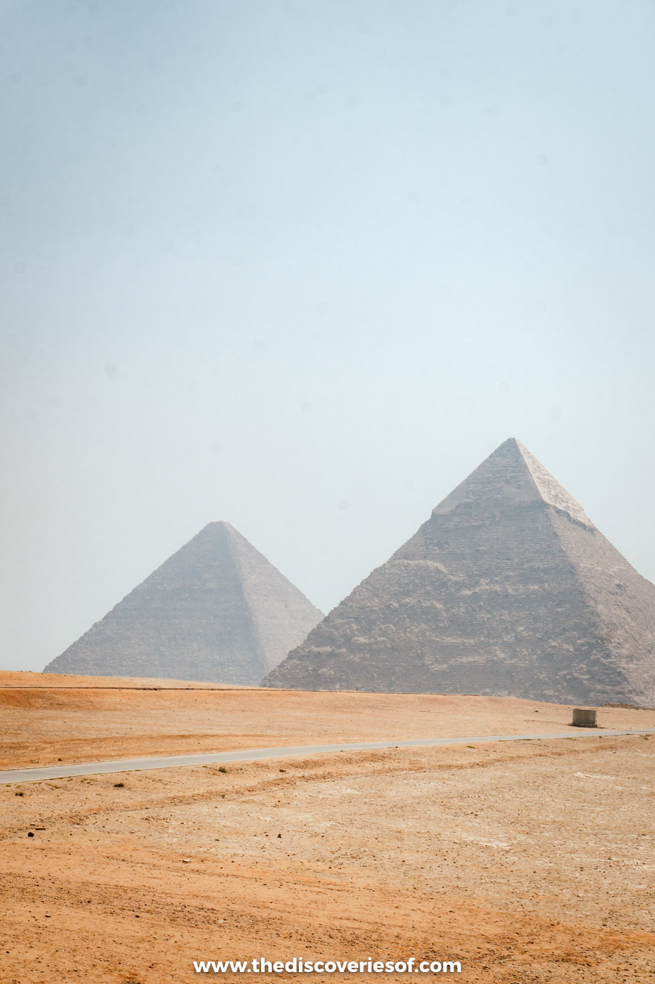 The pyramids of Khafre and Khufu rising above the golden sand of the desert at Giza under a pale sky
