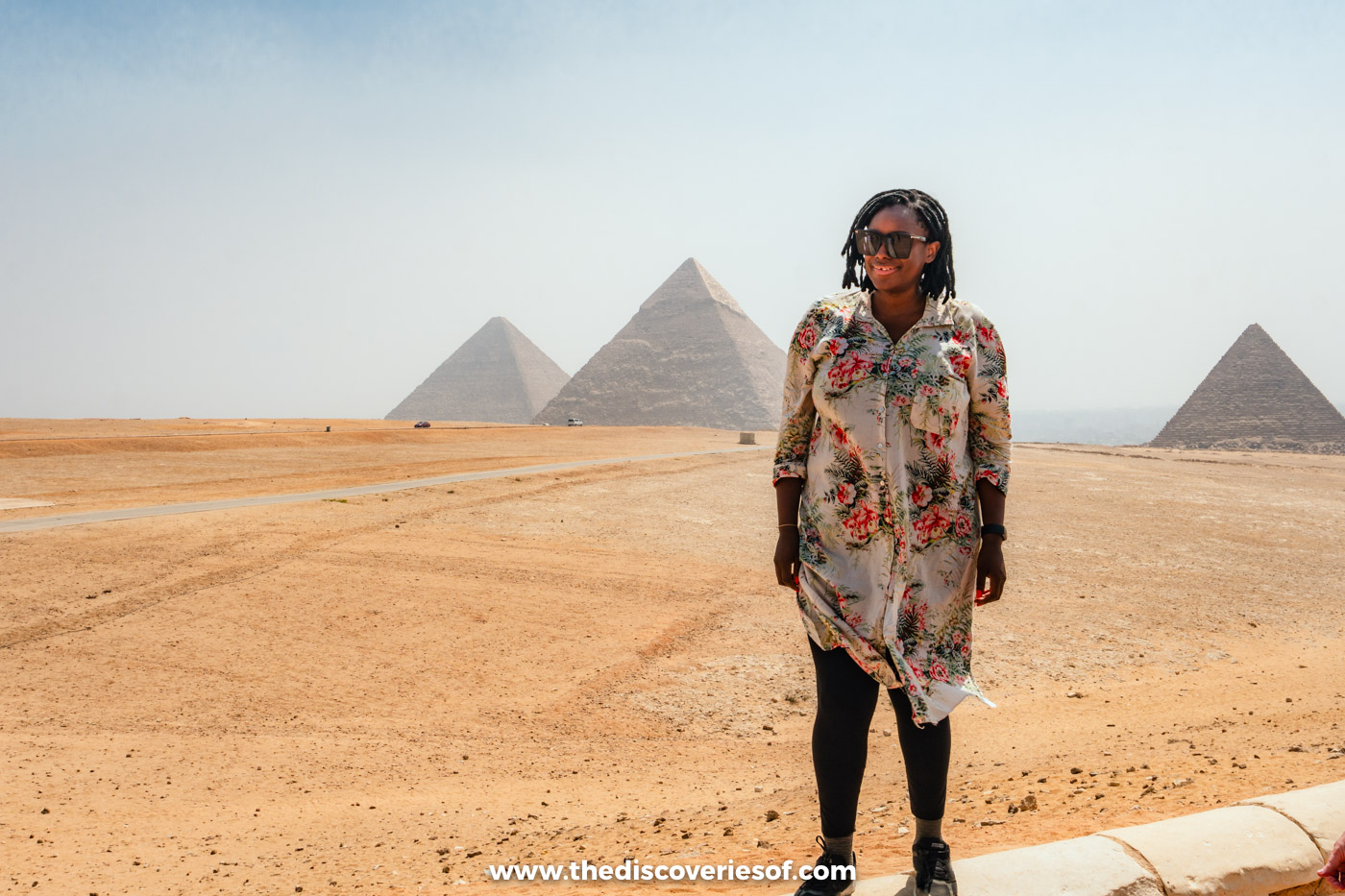 Julianna standing in the desert at the Giza panoramic point with the three pyramids on the horizon behind her