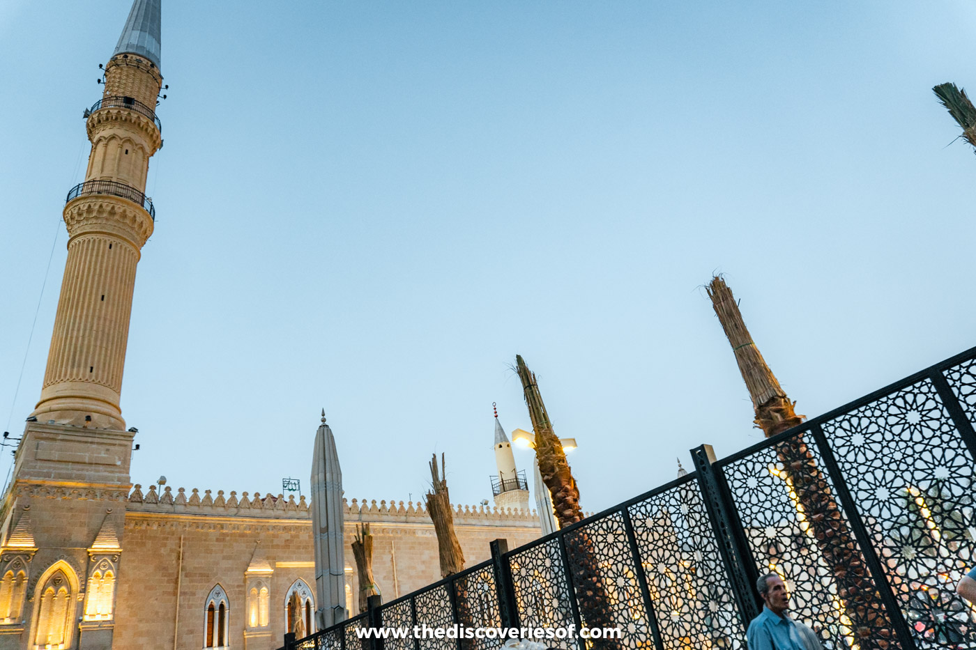 The minaret of the Al-Hussein Mosque in Islamic Cairo lit up at dusk beside the square