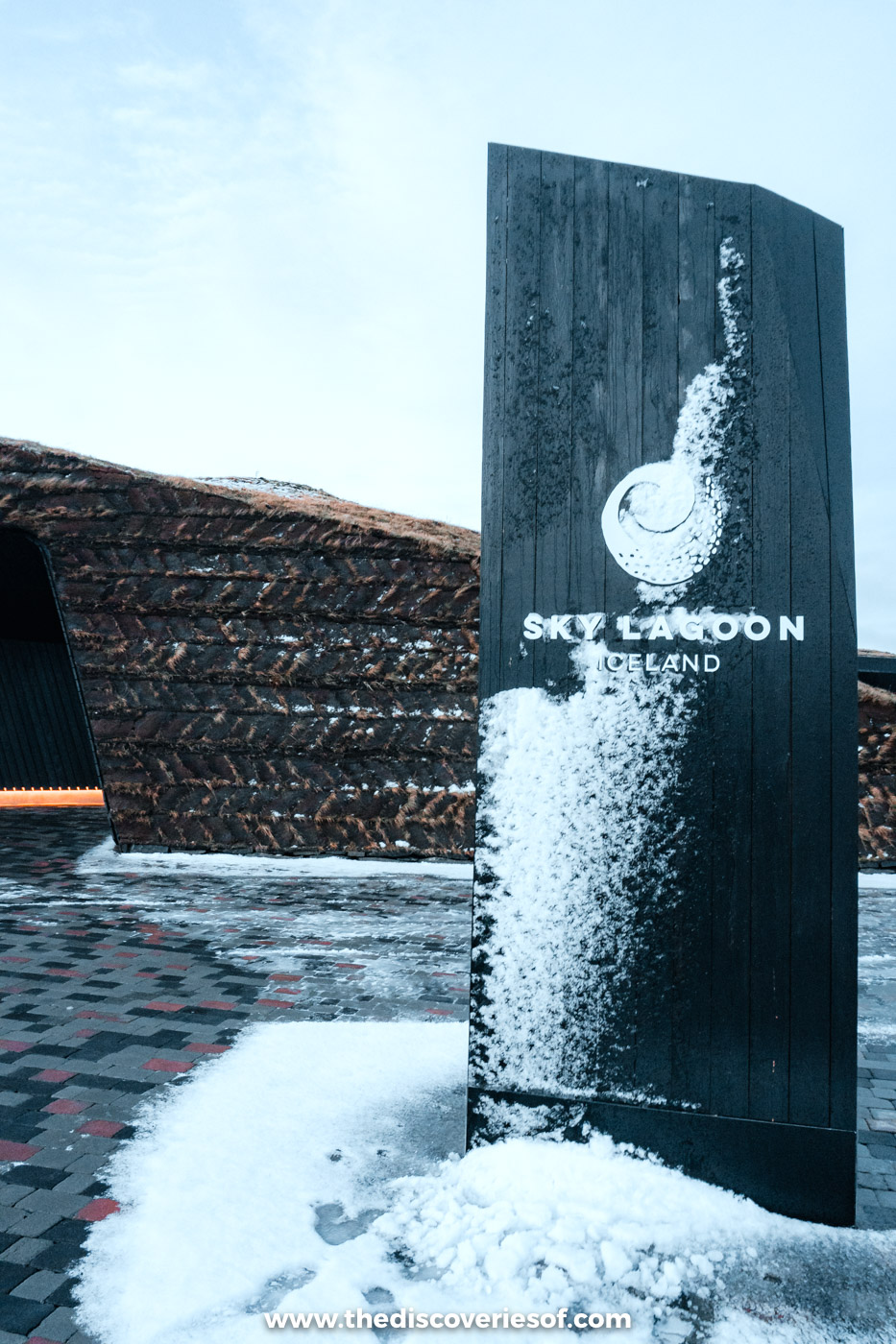The tall dark Sky Lagoon entrance sign dusted with fresh snow in December, Kópavogur, near Reykjavik