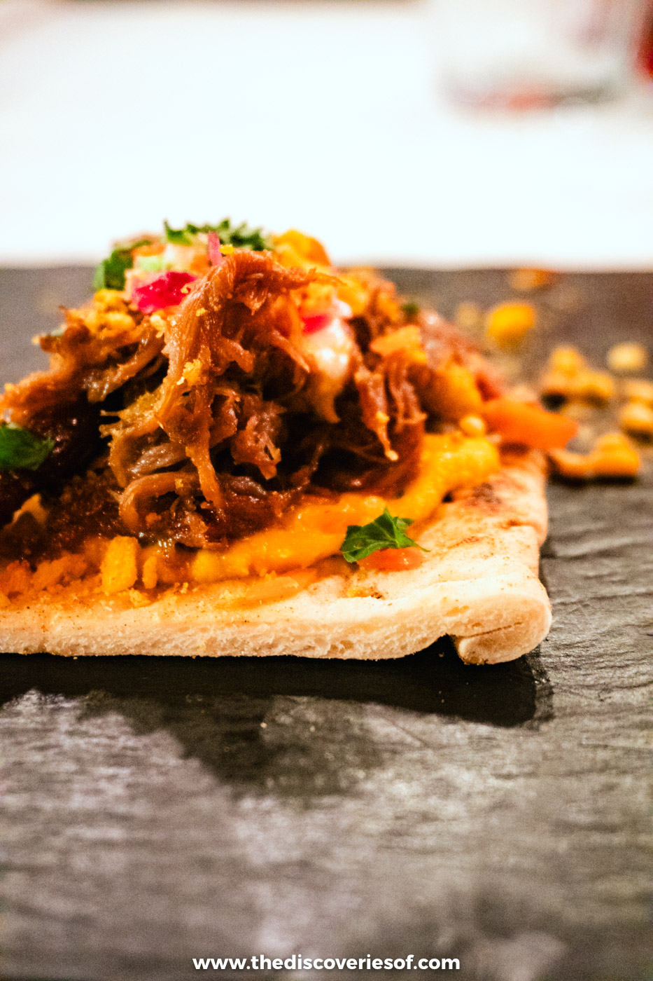 Pulled meat topped with herbs and pickles on a flatbread served in a Reykjavik restaurant in December